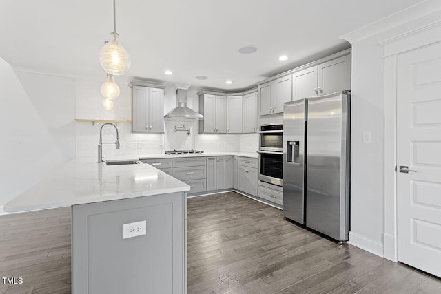 kitchen featuring sink, hanging light fixtures, appliances with stainless steel finishes, kitchen peninsula, and wall chimney range hood