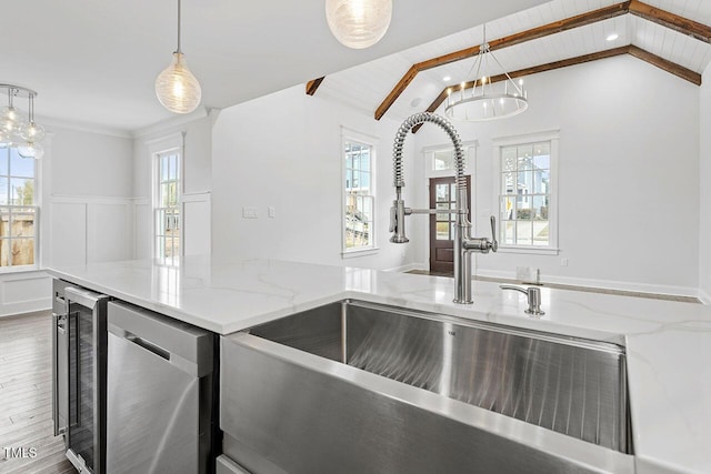 kitchen featuring sink, beverage cooler, hanging light fixtures, stainless steel dishwasher, and light stone counters