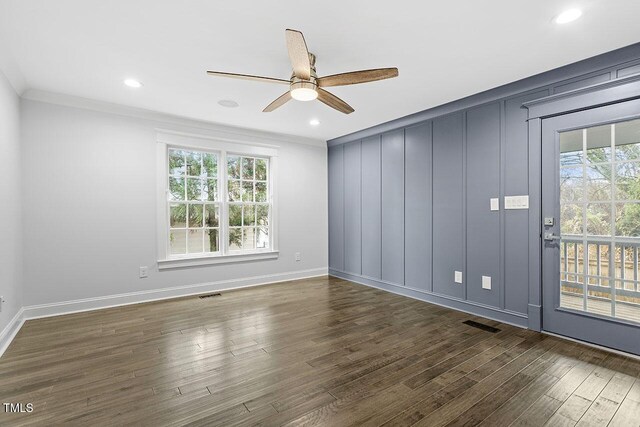 empty room featuring ornamental molding, a healthy amount of sunlight, and dark wood-type flooring