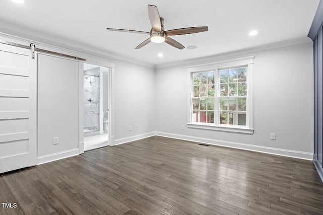 unfurnished room featuring ornamental molding, a barn door, dark wood-type flooring, and ceiling fan