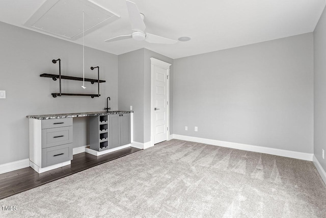 unfurnished bedroom with dark colored carpet, sink, and ceiling fan