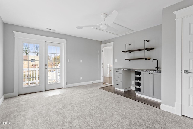 interior space with ceiling fan, sink, carpet floors, and stone counters