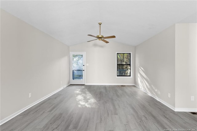 empty room with vaulted ceiling, ceiling fan, baseboards, and wood finished floors