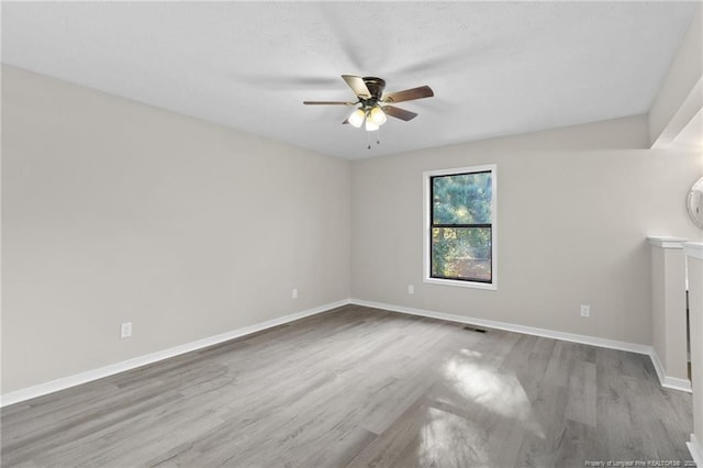 unfurnished room with visible vents, baseboards, wood finished floors, a textured ceiling, and a ceiling fan