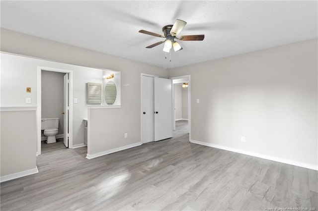 unfurnished bedroom with ceiling fan, wood finished floors, baseboards, and connected bathroom