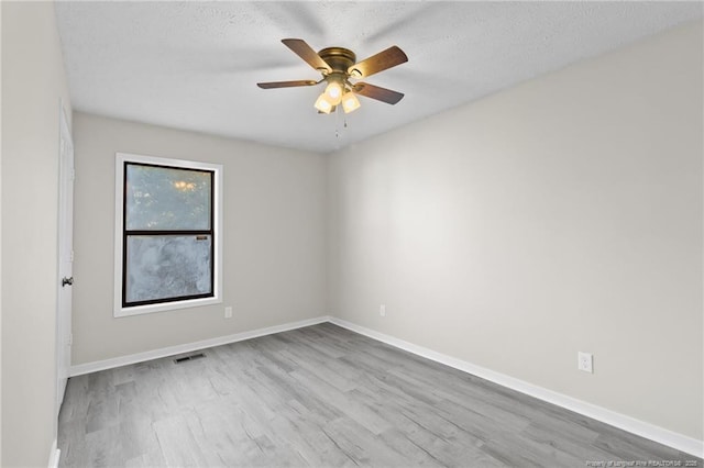 unfurnished room with ceiling fan, a textured ceiling, baseboards, and wood finished floors