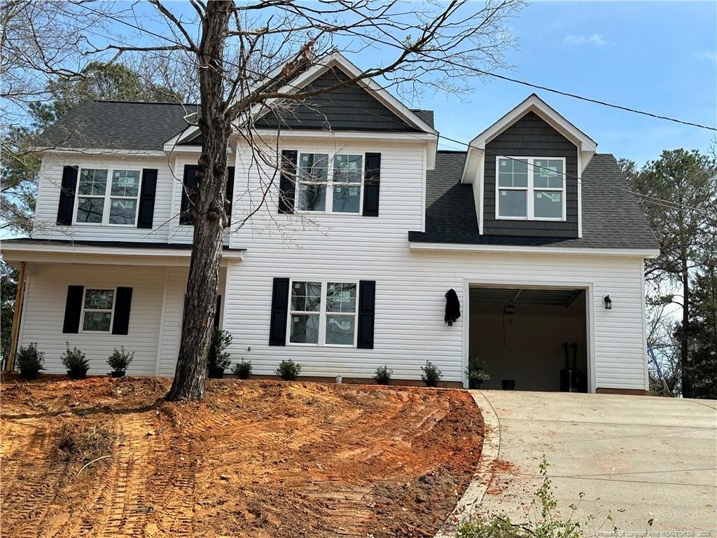 view of front facade featuring a garage, driveway, and roof with shingles