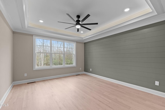 empty room with light hardwood / wood-style flooring and a tray ceiling