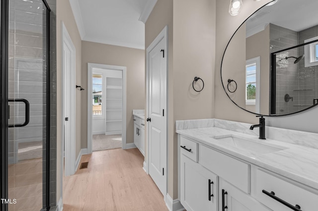 bathroom featuring hardwood / wood-style flooring, plenty of natural light, an enclosed shower, and ornamental molding