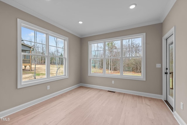 empty room with crown molding and light hardwood / wood-style flooring