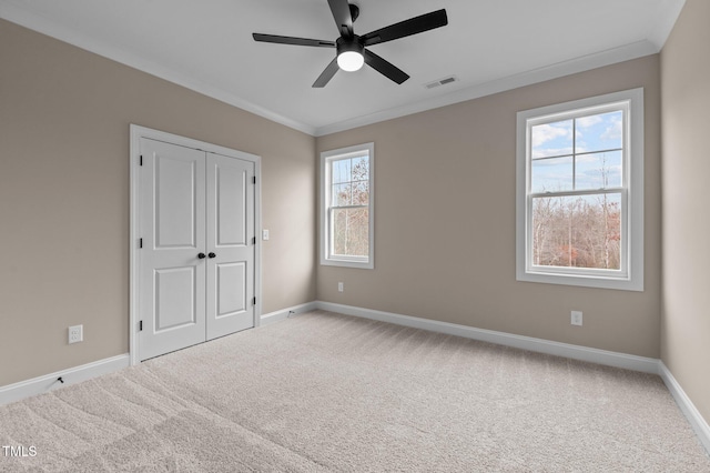 unfurnished bedroom with carpet flooring, ceiling fan, crown molding, and a closet