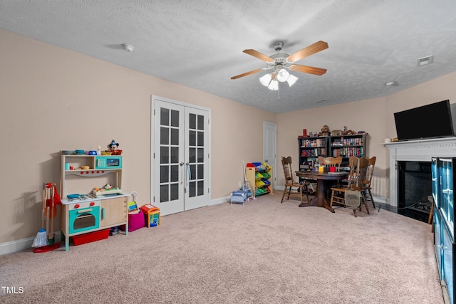 playroom with ceiling fan, carpet floors, a textured ceiling, and french doors