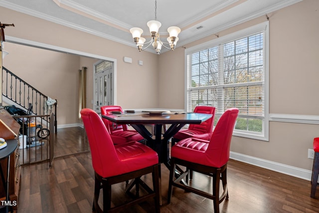 dining room with a raised ceiling, dark hardwood / wood-style floors, an inviting chandelier, and ornamental molding