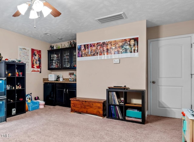 rec room with light carpet, ceiling fan, and a textured ceiling