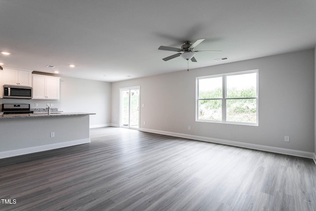 unfurnished living room with ceiling fan, sink, and dark wood-type flooring