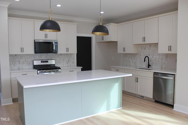 kitchen featuring decorative light fixtures, a kitchen island, sink, and stainless steel appliances