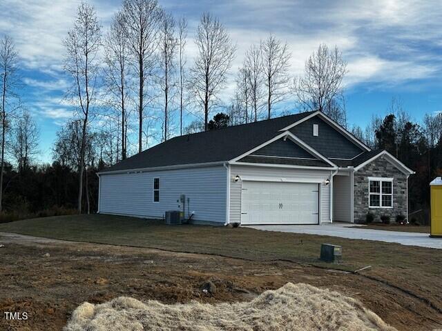 view of property exterior featuring a garage, cooling unit, and a lawn