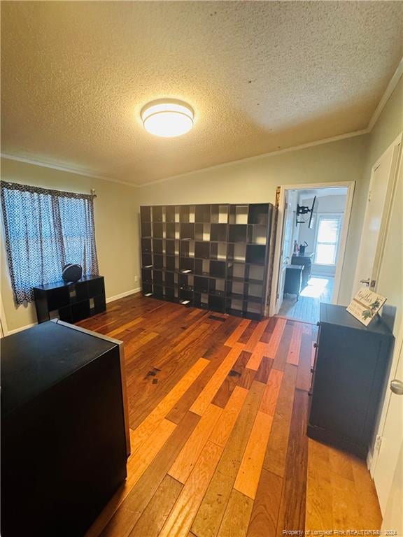 interior space featuring lofted ceiling, a textured ceiling, light hardwood / wood-style floors, and ornamental molding