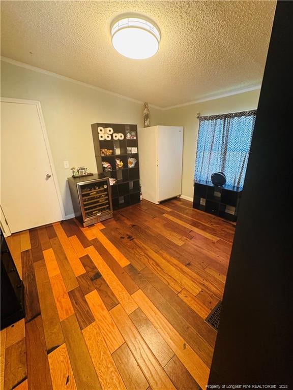 interior space with wood-type flooring, a textured ceiling, and ornamental molding