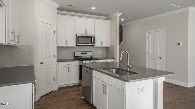 1825 Hinesley Dr, Durham, NC 27703 - kitchen with appliances with stainless steel finishes, a sink, crown molding, dark countertops, and dark wood-style floors