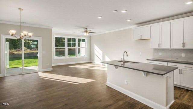 1825 Hinesley Dr, Durham, NC 27703 - kitchen with dark countertops, ornamental molding, a sink, tasteful backsplash, and dark wood finished floors