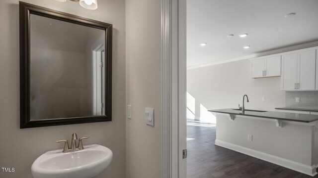 1825 Hinesley Dr, Durham, NC 27703 - bathroom with a sink, wood finished floors, baseboards, crown molding, and recessed lighting
