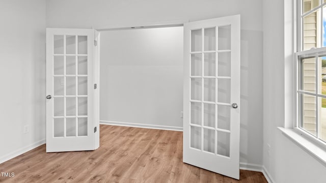 unfurnished room featuring french doors and light wood-type flooring