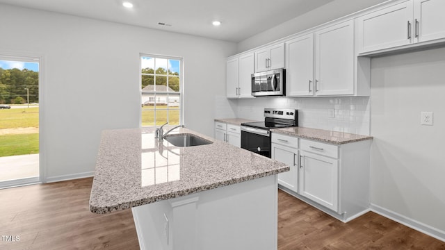 kitchen with appliances with stainless steel finishes, an island with sink, white cabinetry, and sink