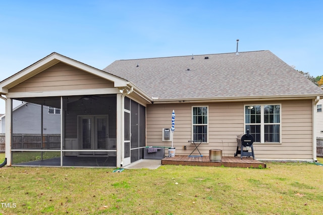 rear view of house with a yard, a wooden deck, and a sunroom