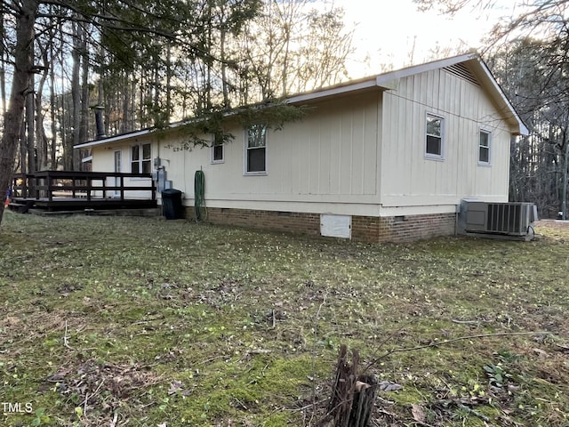 view of side of home featuring a wooden deck, central AC unit, and a lawn