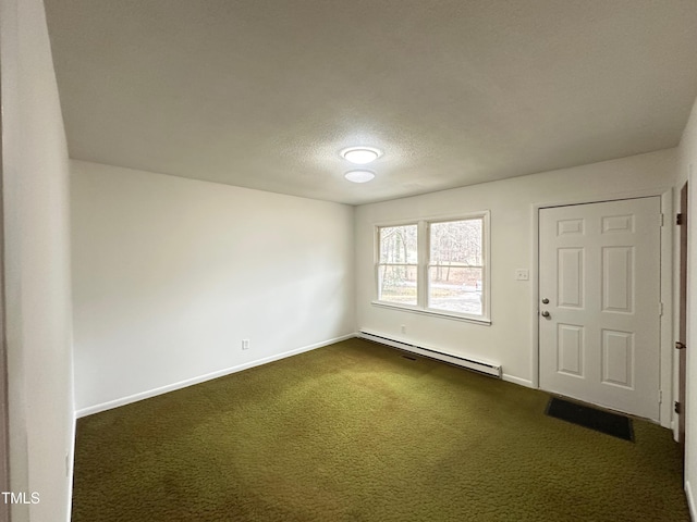 carpeted empty room featuring a textured ceiling and a baseboard heating unit