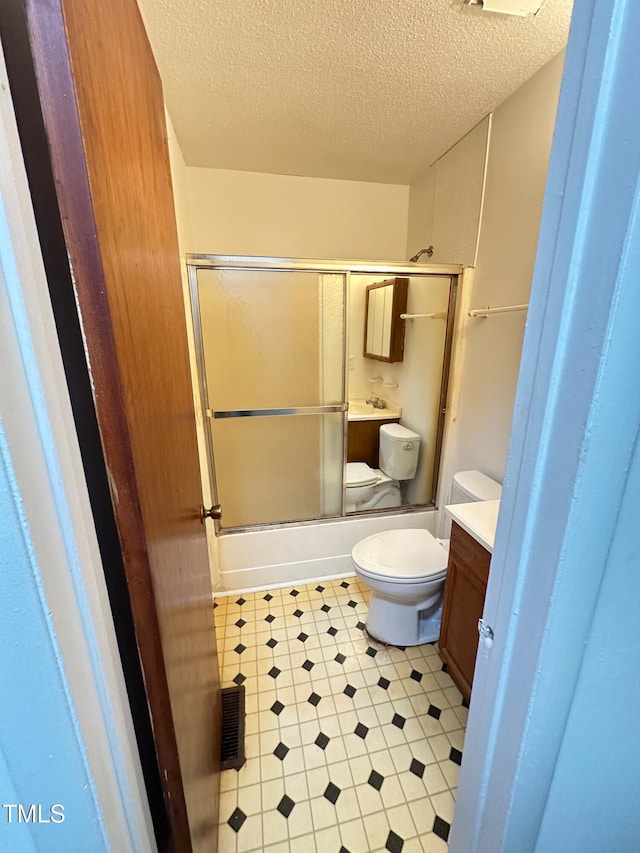 full bathroom featuring enclosed tub / shower combo, vanity, toilet, and a textured ceiling