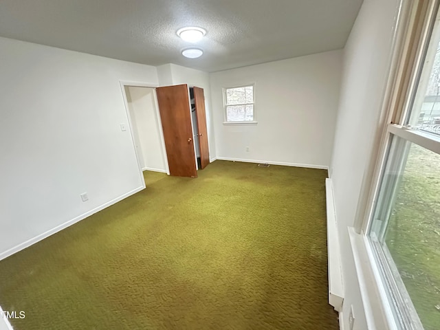 carpeted empty room featuring a textured ceiling