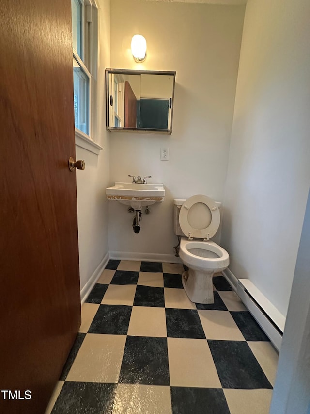 bathroom with baseboard heating, toilet, and sink