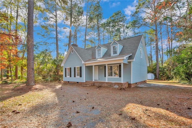 cape cod-style house with covered porch and a storage shed