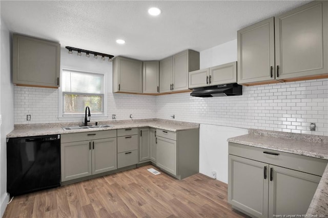 kitchen with decorative backsplash, sink, light wood-type flooring, and black dishwasher