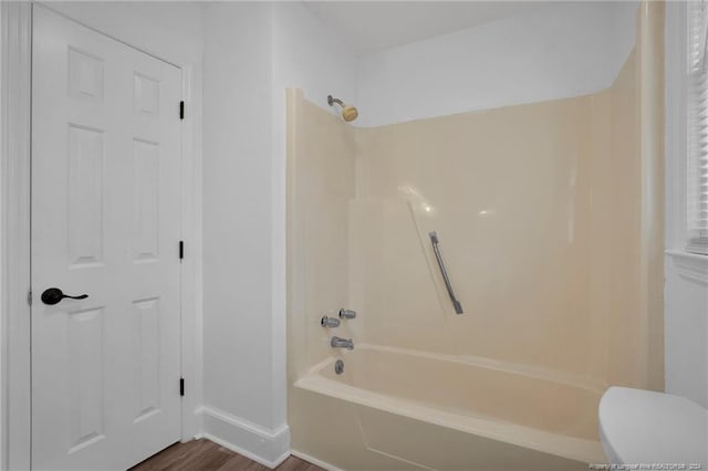 bathroom featuring shower / bath combination, hardwood / wood-style flooring, and toilet