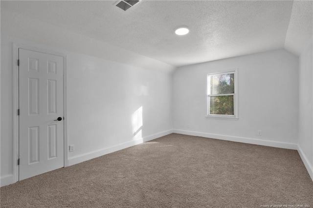 carpeted spare room featuring a textured ceiling and lofted ceiling