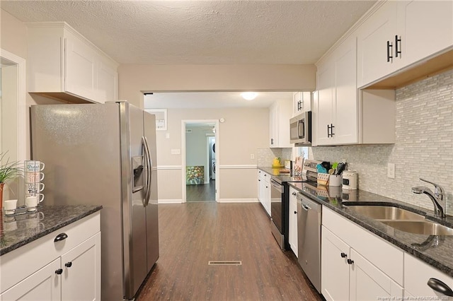 kitchen with white cabinets, appliances with stainless steel finishes, dark hardwood / wood-style floors, and sink