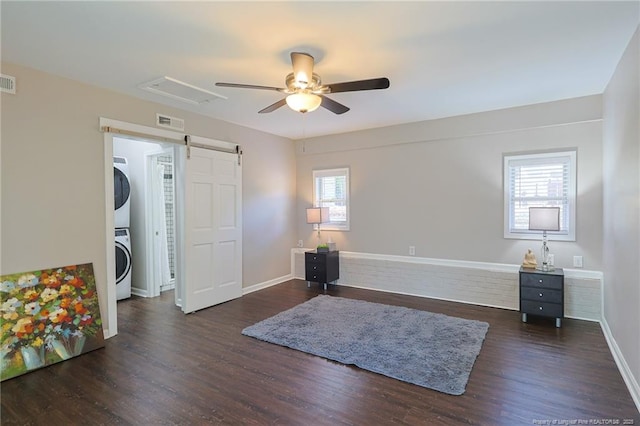 interior space with stacked washing maching and dryer, plenty of natural light, dark hardwood / wood-style flooring, and a barn door