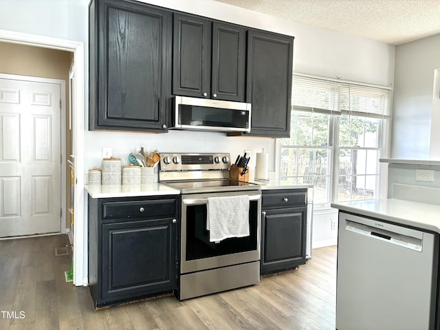 kitchen featuring stainless steel appliances, a textured ceiling, and light wood-type flooring