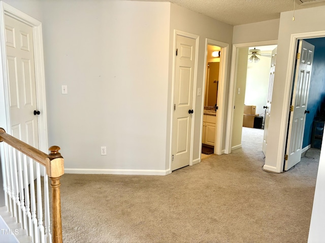 corridor with light colored carpet and a textured ceiling