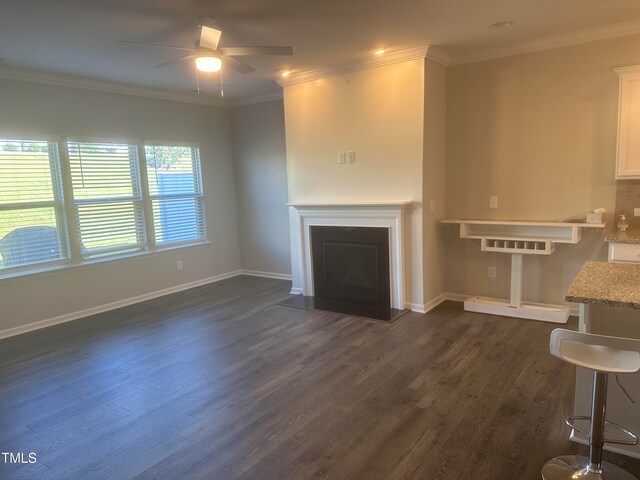 unfurnished living room featuring dark hardwood / wood-style floors, ceiling fan, and crown molding