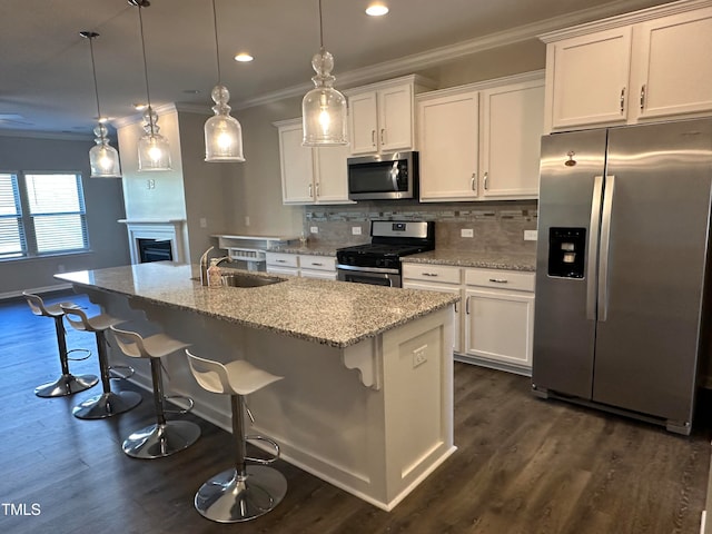 kitchen featuring decorative light fixtures, a kitchen island with sink, sink, and appliances with stainless steel finishes