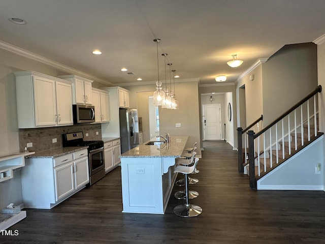 kitchen featuring sink, an island with sink, appliances with stainless steel finishes, dark hardwood / wood-style flooring, and white cabinetry