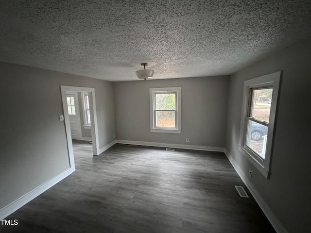 spare room featuring dark hardwood / wood-style flooring and a textured ceiling