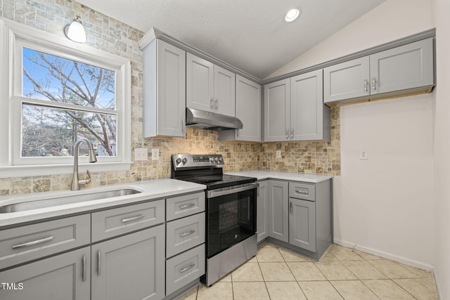 kitchen with gray cabinetry, stainless steel electric range, sink, and vaulted ceiling