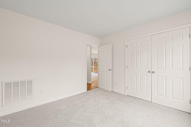 unfurnished bedroom with a closet and light colored carpet