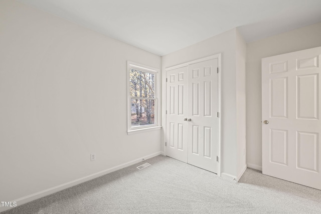 unfurnished bedroom featuring light carpet and a closet