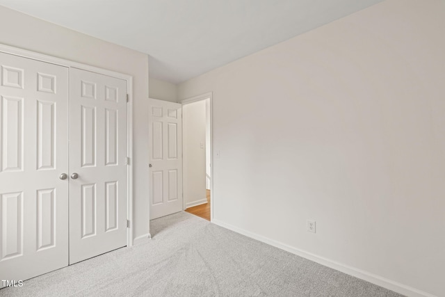 unfurnished bedroom with light carpet and a closet